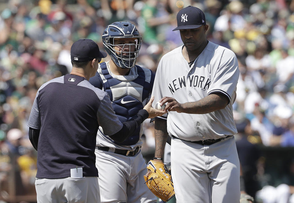 New York Yankees pitcher CC Sabathia, right, hands the ball to manager Aaron Boone, left, as he is relieved during the fourth inning of a baseball game against the Oakland Athletics in Oakland, Calif., Monday, Sept. 3, 2018. Also pictured is catcher Gary Sanchez, center. (AP Photo/Jeff Chiu)