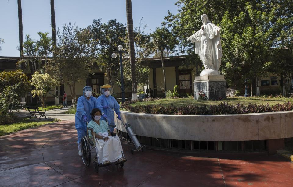 Nurses wearing protective gear take a patient out for fresh air who is staying in the intensive care unit for people infected with the new coronavirus, at the 2 de Mayo Hospital, in Lima, Peru, Friday, April 17, 2020. (AP Photo/Rodrigo Abd)