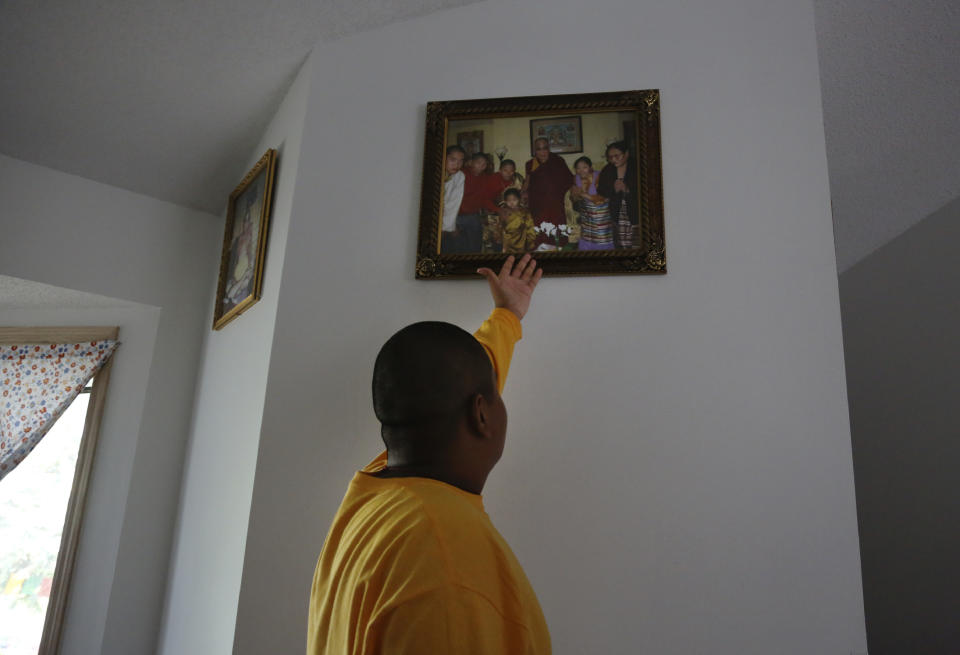 Jalue Dorje, 14, points to a photograph of his family with the Dalai Lama that hangs in the entryway of his family's home in Columbia Heights, Minn., on Tuesday, July 20, 2021. When he was an infant, Jalue, now 14, was identified as the eighth reincarnation of the lama Terchen Taksham Rinpoche. After finishing high school in 2025, Jalue will head to northern India and join the Mindrolling Monastery, more than 7,200 miles (11,500 kilometers) from his home. (AP Photo/Jessie Wardarski)