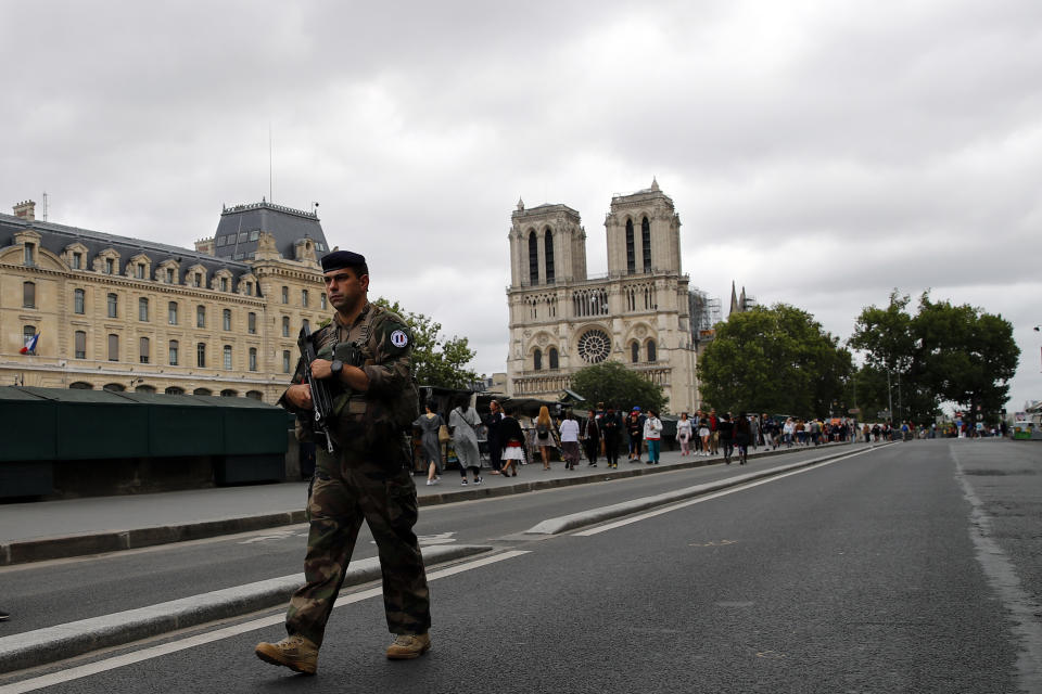 French soldier patrols as Catholic pilgrims take part in an emotional procession with the statue of the Virgin Mary rescued from the April blaze past the fire-ravaged Notre Dame Cathedral to celebrate the Assumption of the Virgin in Paris, Thursday, Aug. 15, 2019. (AP Photo/Francois Mori)