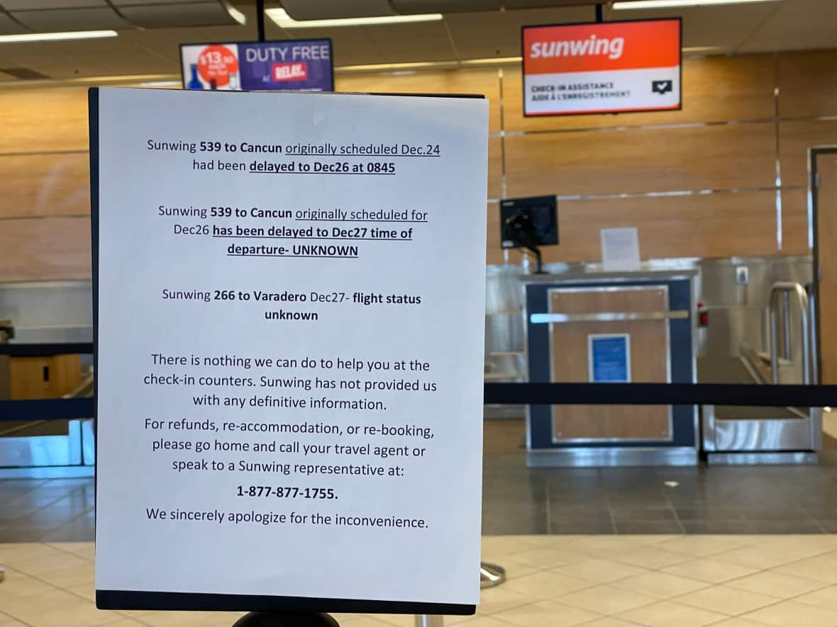 A sign at an empty Sunwing kiosk at Regina Airport on Monday afternoon details the status of some past flights. (Kirk Fraser/CBC - image credit)