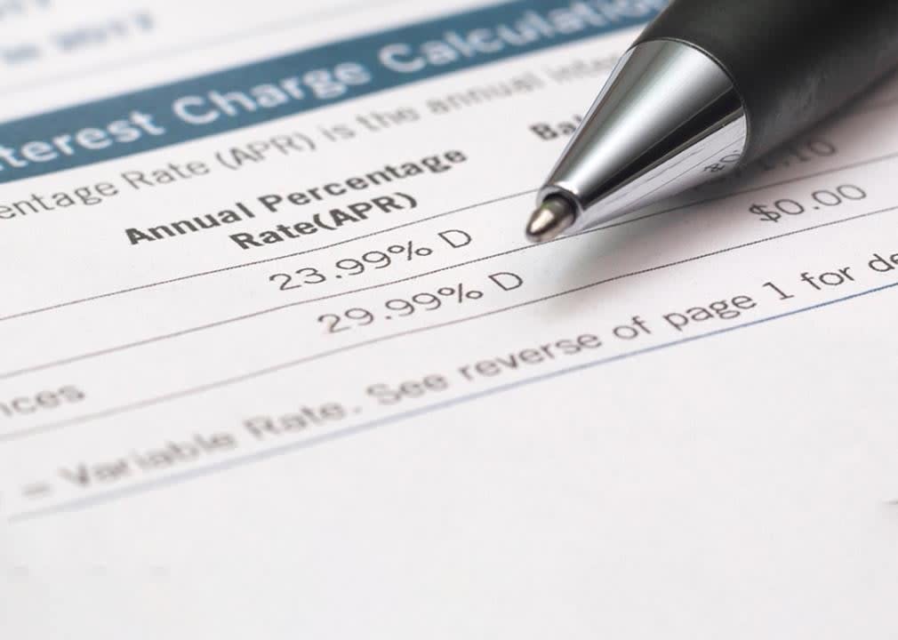 paper bank statement showing 23.9% APR with pen in background