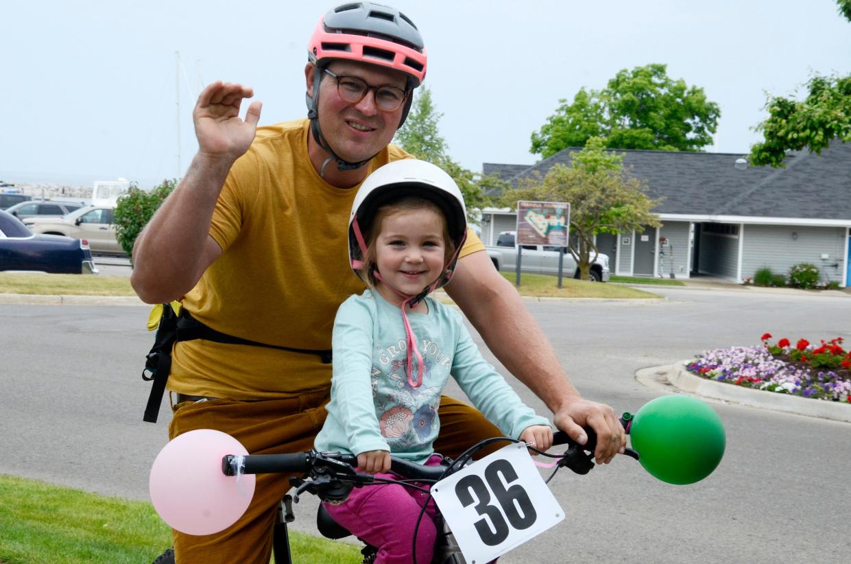 Tim and Olive Grimes of Petoskey wave as they ride past in the bike parade on Saturday, June 10, 2023 during the first annual Lynn Duse Memorial Kids’ Bike Fest.