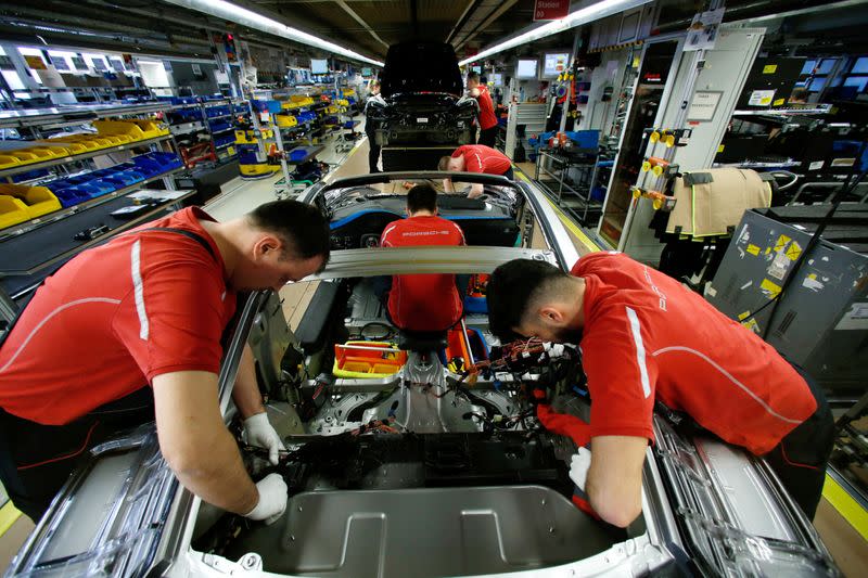 FILE PHOTO: Employees of German car manufacturer Porsche work on a Porsche 911 at the Porsche factory in Stuttgart-Zuffenhausen