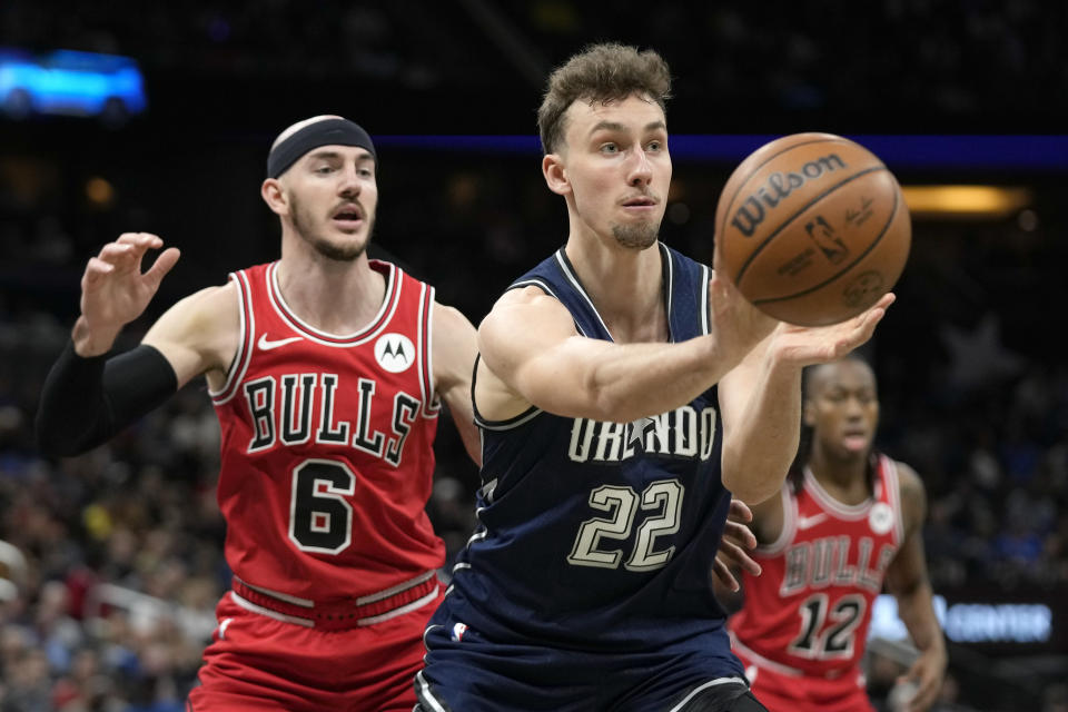 Orlando Magic forward Franz Wagner (22) passes the ball as he is defended by Chicago Bulls guard Alex Caruso (6) during the first half of an NBA basketball game, Saturday, Feb. 10, 2024, in Orlando, Fla. (AP Photo/John Raoux)