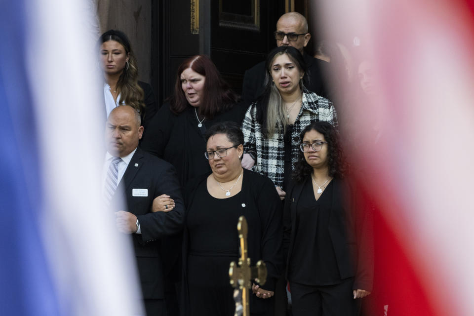 Alex Mendez, bottom center, leaves the viewing and funeral service for her husband, officer Richard Mendez, alongside daughter Mia Mendez at the Cathedral Basilica of Saints Peter and Paul in Philadelphia, Tuesday, Oct. 24, 2023. Mendez was shot and killed, and a second officer was wounded when they confronted people breaking into a car at Philadelphia International Airport, Oct. 12, police said. (AP Photo/Joe Lamberti)