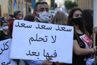 An anti-government protester holds an Arabic placard that reads: "Saad don't dream on it any more," during a protest to denouncing the naming of former Prime minister Saad Hariri as a potential candidate as the country's new prime minister, in downtown Beirut, Lebanon, Wednesday, Oct. 21, 2020. Hariri resigned a year ago amid nationwide protests against government corruption and mismanagement of Lebanon's resources. (AP Photo/Hussein Malla)