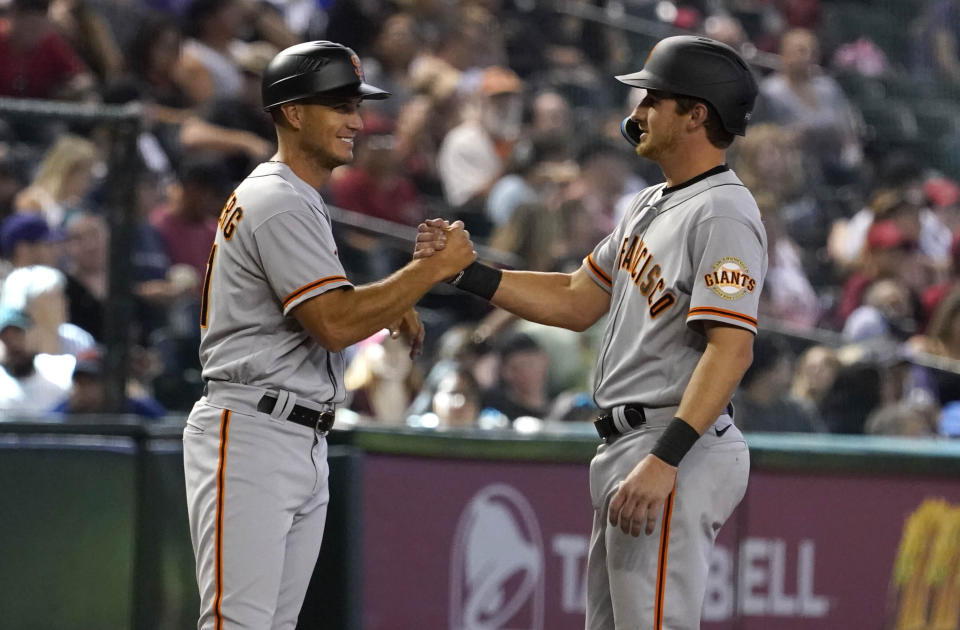 San Francisco Giants third base coach Mark Hallberg, left, congratulates Ford Proctor, right, for getting his first hit in the major leagues in the seventh inning of a baseball game against the Arizona Diamondbacks Sunday Sept. 25, 2022, in Phoenix. (AP Photo/Darryl Webb)