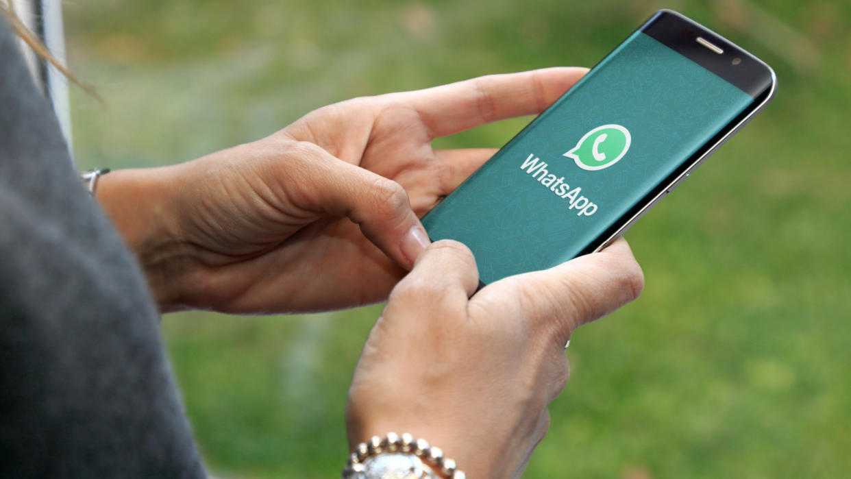  a person holding a phone with the WhatsApp logo on it 