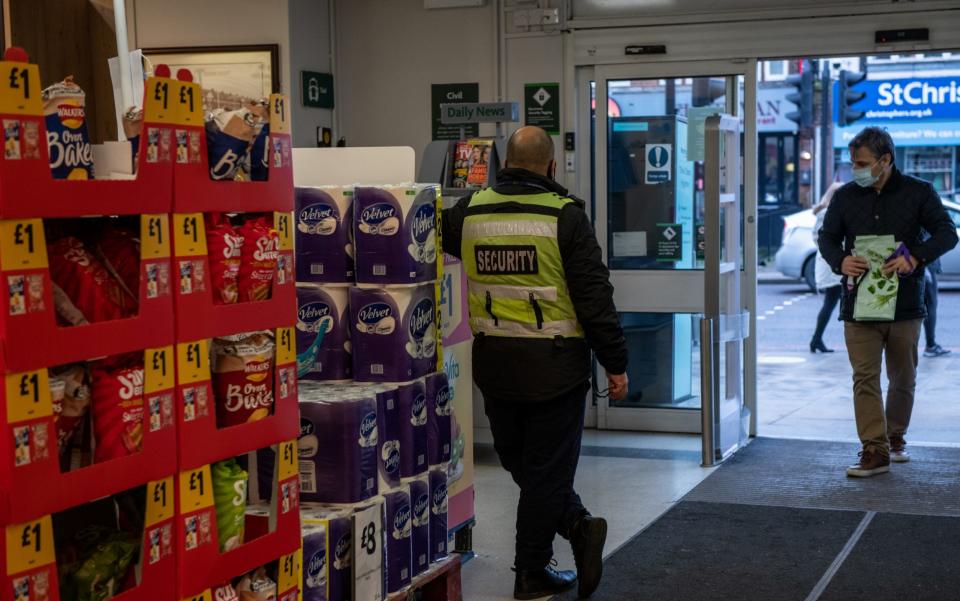 A security guard stands by the entrance to a Morrisons supermarket - Getty