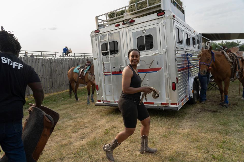 Staci Russell, 39, center, of Belleville, walks back to her horse after borrowing an item from another rider during the local 2023 Midwest Invitational Rodeo at the Wayne County Fairgrounds in Belleville on Saturday, June 10, 2023.