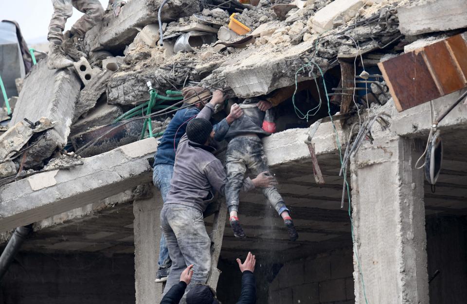 Residents retrieve an injured girl from the rubble of a collapsed building following an earthquake in the town of Jandaris, in the countryside of Syria's northwestern city of Afrin in the rebel-held part of Aleppo province, on February 6, 2023. / Credit: RAMI AL SAYED/AFP via Getty Images