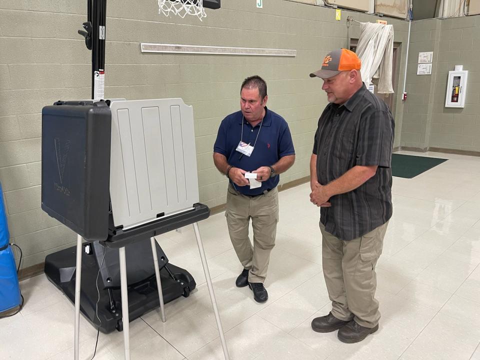Woodlawn election worker JR Kelly, left, assists voter Brian Kisor at one of the voting booths.