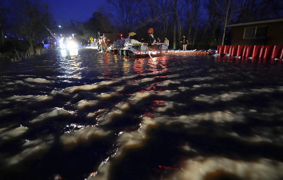 People work to protect homes into the night along 1700 South in Salt Lake City from the rising flow of Emigration Creek through Wasatch Hollow Park on Wednesday, April 12, 2023. As rapid snowmelt and possible April showers stoke fears of heavy flooding in the Northern Plains, state officials are announcing flood response plans, and residents are assembling thousands — if not hundreds of thousands — of sandbags to combat floods themselves. (Francisco Kjolseth/The Salt Lake Tribune via AP)