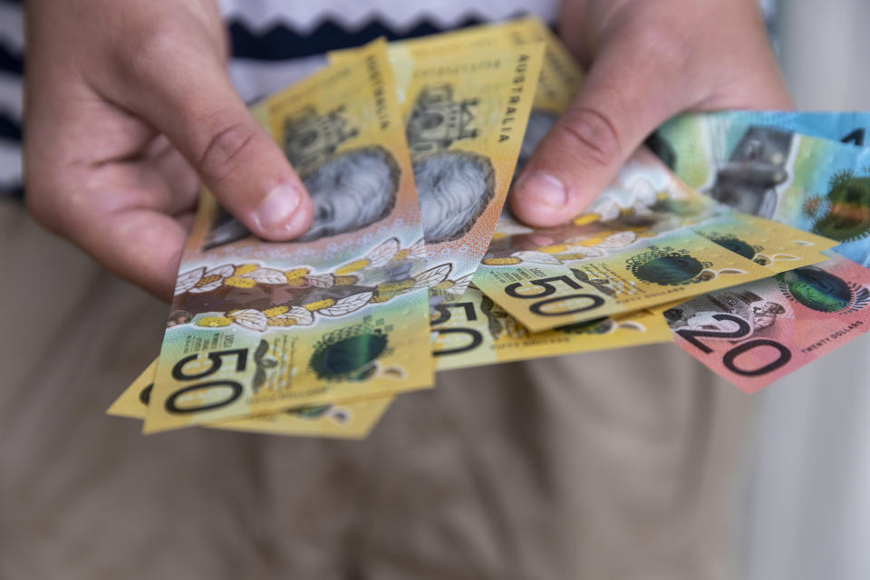 Male person holding some Australian currency. This visual concept evokes ideas around saving money, paying for expenses and investments.