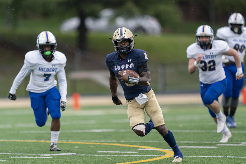 Gallaudet quarterback Brandon Washington, center, runs toward the end zone to make the first touchdown scored while wearing a football helmet that helps Deaf and hard-of-hearing players see play calls on a lens inside during an NCAA college football game against Hilbert College, Saturday, Oct. 7, 2023, in Washington. (AP Photo/Stephanie Scarbrough)