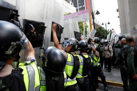 Riot police officers rise their shields as they escort people walking out from the National Assembly after a session in Caracas, Venezuela October 27, 2016. REUTERS/Carlos Garcia Rawlins
