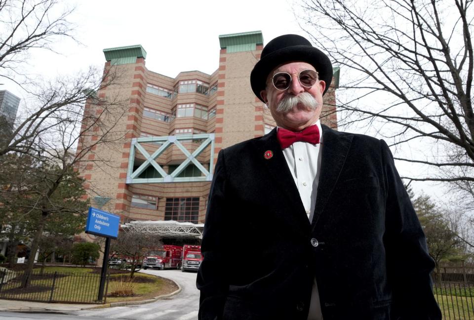 Vin Marzullo works as a volunteer at Hasbro Children's Hospital in Providence, shown in the background. Folks think he looks like "Rich Uncle" Pennybags (Milburn Pennybags), the cartoon mascot for the Monopoly board game, so he's decided to go with it. “If the Monopoly Man makes them smile," he says, "I can’t shut it down.”