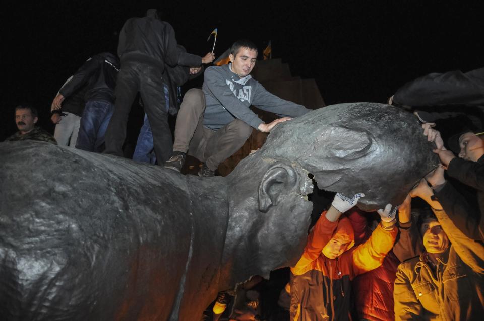 People react after a statue of Soviet state founder Vladimir Lenin was toppled by protesters during a rally organized by pro-Ukraine supporters in the centre of the eastern Ukrainian town of Kharkiv September 28, 2014. Picture taken September 28, 2014. REUTERS/Stringer (UKRAINE - Tags: POLITICS CIVIL UNREST TPX IMAGES OF THE DAY)