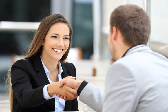 Smiling woman shaking hands with man.