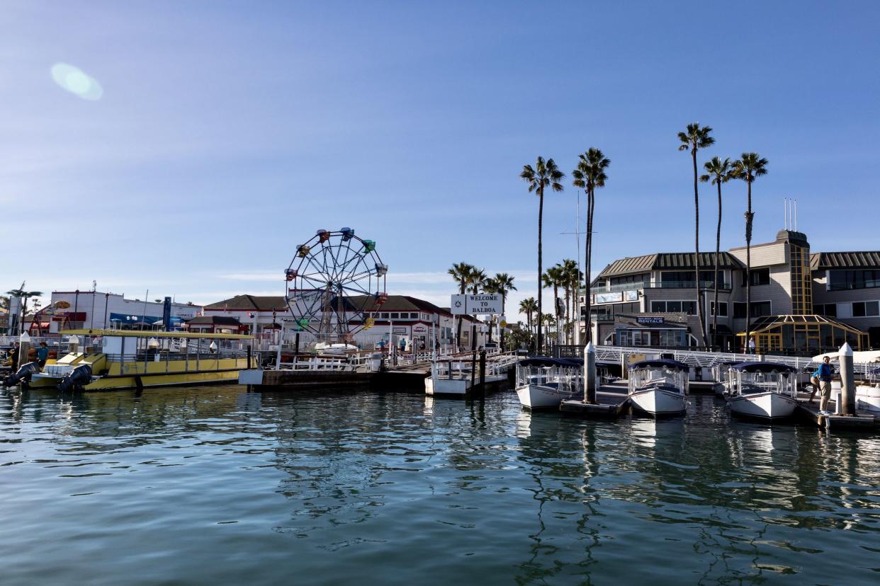 Newport Beach, CA - January 26, 2019: The Balboa Fun zone on Balboa Island in Newport Beach California showing boats moored, a Ferris wheel and a ferry boat dock. The Balboa Fun zone has restaurants and entertainment for adults and children