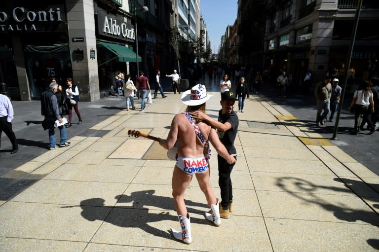 Robert John Burck, an American street performer known as the Naked Cowboy, poses with a young fan during a visit to Madero street in Mexico City