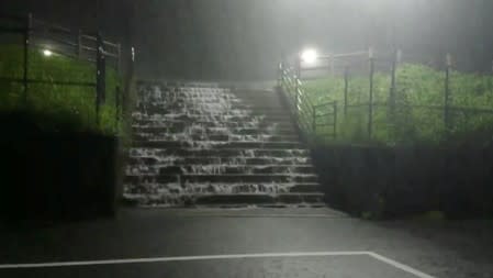 Water flows down a staircase during heavy rains in Miyaki