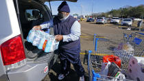 George Moore loads a case of water into his vehicle Wednesday, Jan. 26, 2022, in Jackson, Miss. Moore said the bottles of water addressed a need of his "spiritual mother," who has dealt with the city's low water pressure at home for extended periods and is concerned about its drinking quality. (AP Photo/Rogelio V. Solis)