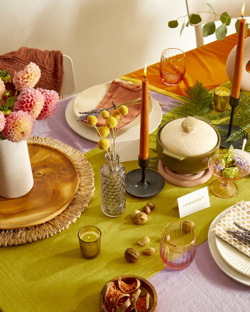 Angled view of a set colorful holiday tablescape with flowers and candles.