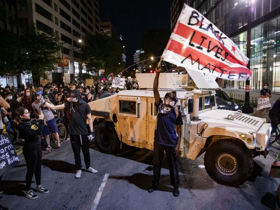 A protester waves a DC flag with Black Lives Matter spray painted on it next to a DC National Guard Humvee as protestors march through the streets during a demonstration over the death of George Floyd on 2 June 2020 in Washington, DC: Samuel Corum/Getty