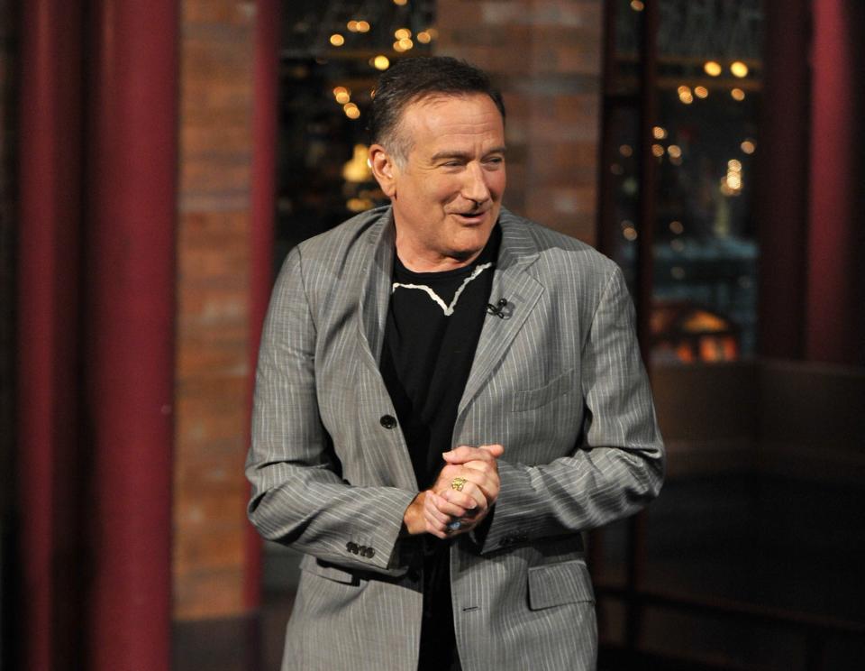 Robin Williams laughing with his hands clasped