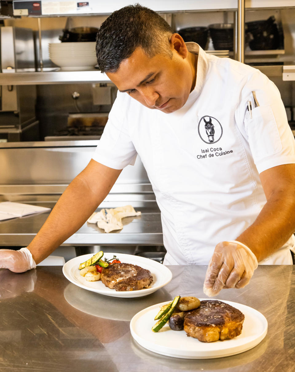 Chef de Cuisine Isai Coca sprinkles course salt on a 16-ounce grilled ribeye steak at Stirrups on July 20. The restaurant is inside The Equestrian Hotel at the World Equestrian Center in Ocala.