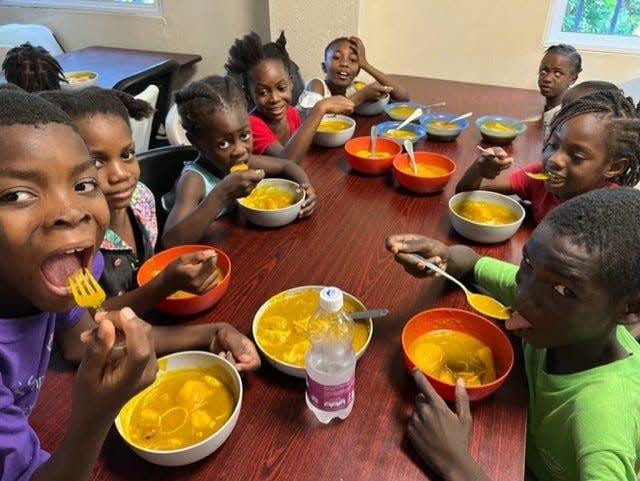 Kids at the Have Faith Haiti Mission & Orphanage enjoy a meal at the table.