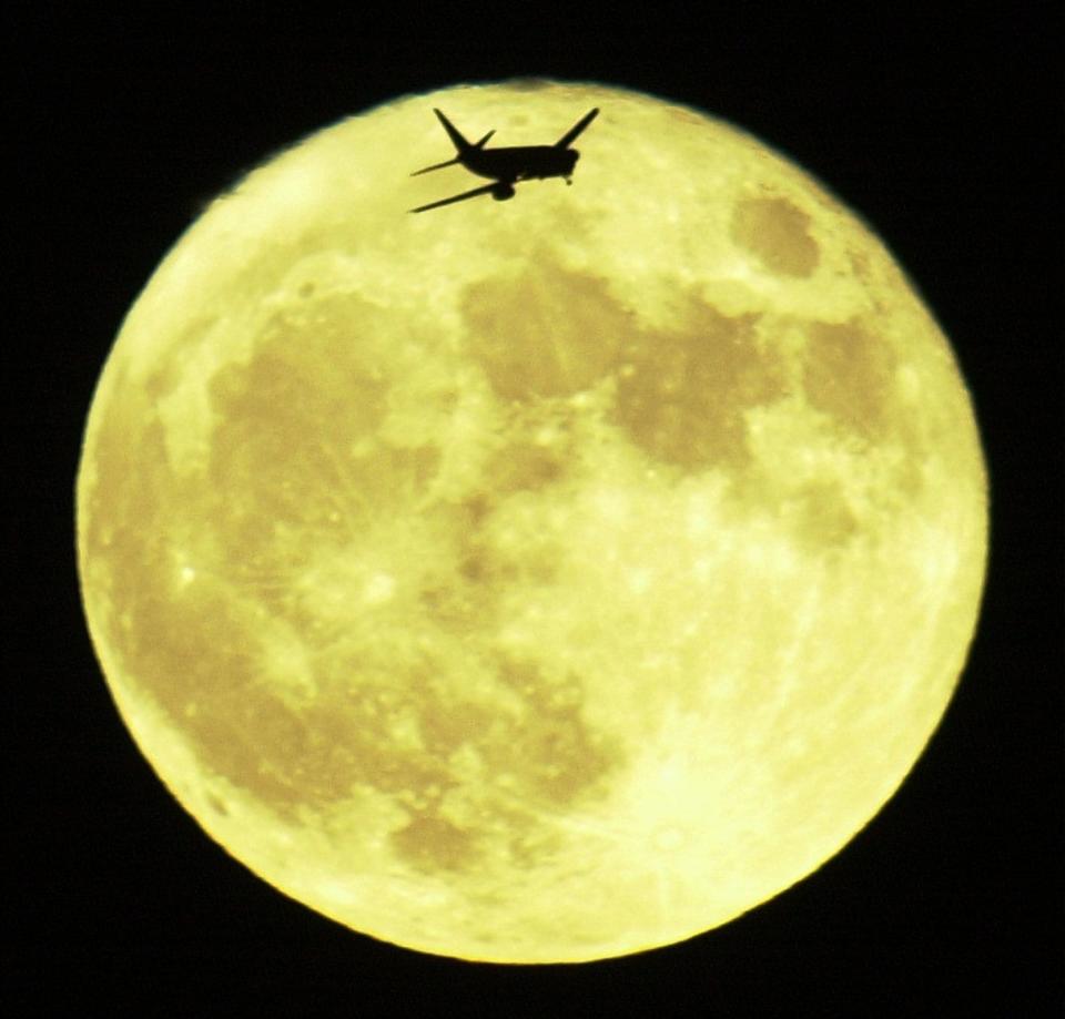 A jet flies in front of the Harvest Moon on approach to Sky Harbor International Airport in Phoenix in September 2002.