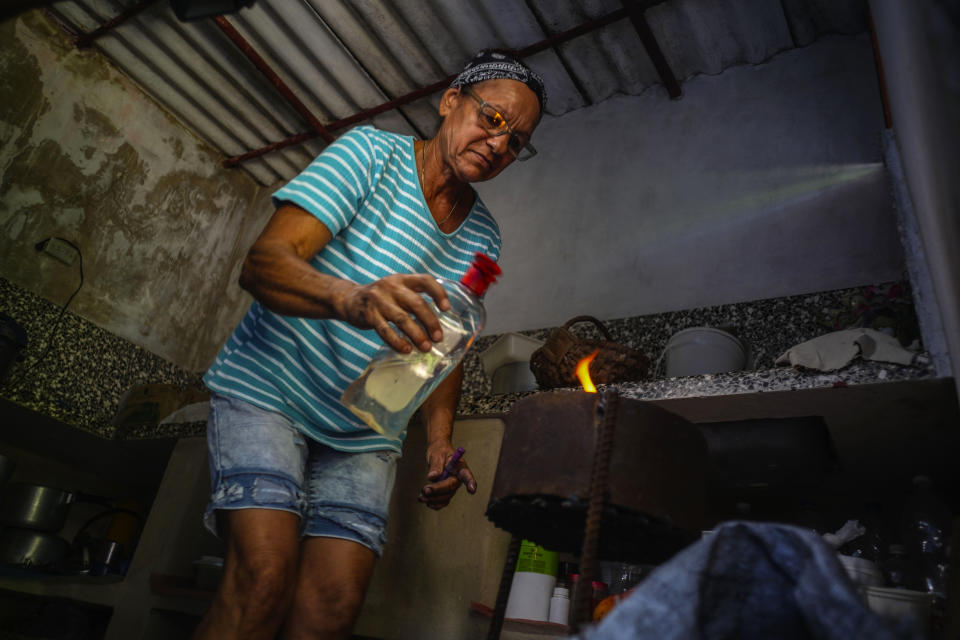 Rosa Lopez lights a charcoal stove to boil sweet potatoes and prepare scrambled eggs with tomatoes for her grandchildren, amid a gas shortage in Mariel, Cuba, Thursday, May 18, 2023. (AP Photo/Ramon Espinosa)