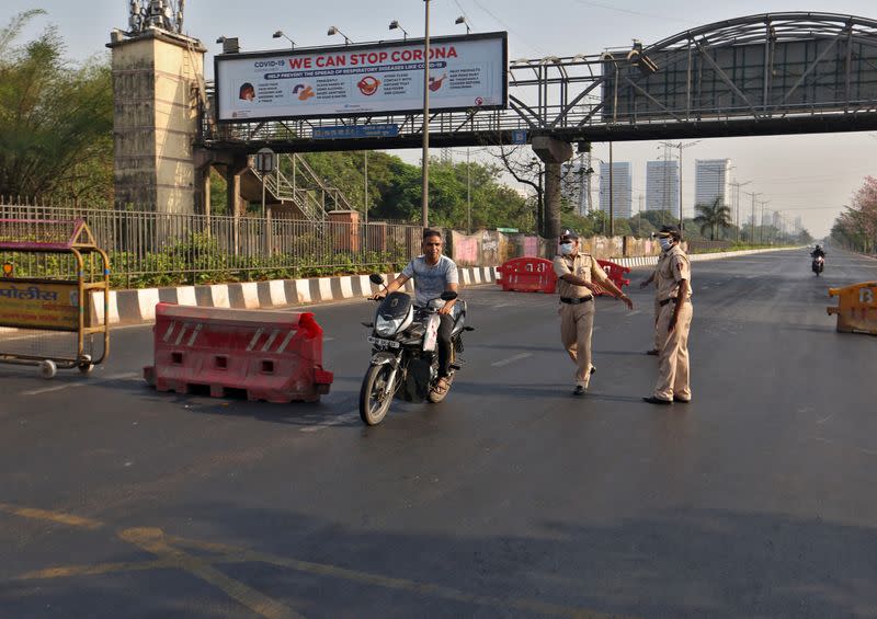 Policem officers try to stop a motorcyclist at a barrier on a road during a curfew to limit the spreading of coronavirus disease (COVID-19), in Mumbai