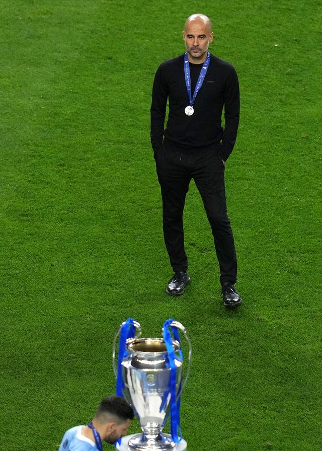 Pep Guardiola looks at the Champions League trophy