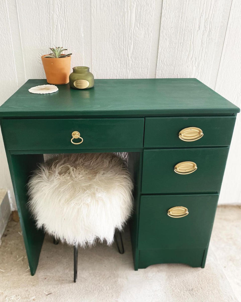 A small vintage bottle green desk with three drawers and gold drawer pulls