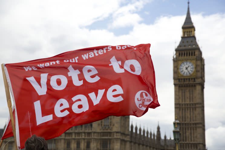 Leave supporters hold flags as they stand on Westminster Bridge during an EU referendum campaign stunt in which a flotilla of boats used by supporters of Leave sailed up the River Thames, outside the Houses of Parliament, in London, June 15, 2016. (AP Photo/Matt Dunham)