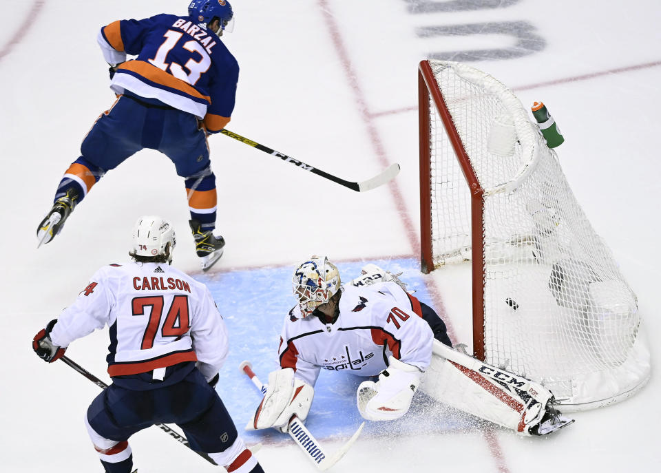 New York Islanders center Mathew Barzal (13) scores the winning goal past Washington Capitals goaltender Braden Holtby (70) as Capitals defenseman John Carlson (74) looks on during overtime NHL Eastern Conference Stanley Cup playoff hockey action in Toronto, Sunday, Aug. 16, 2020. (Nathan Denette/The Canadian Press via AP)