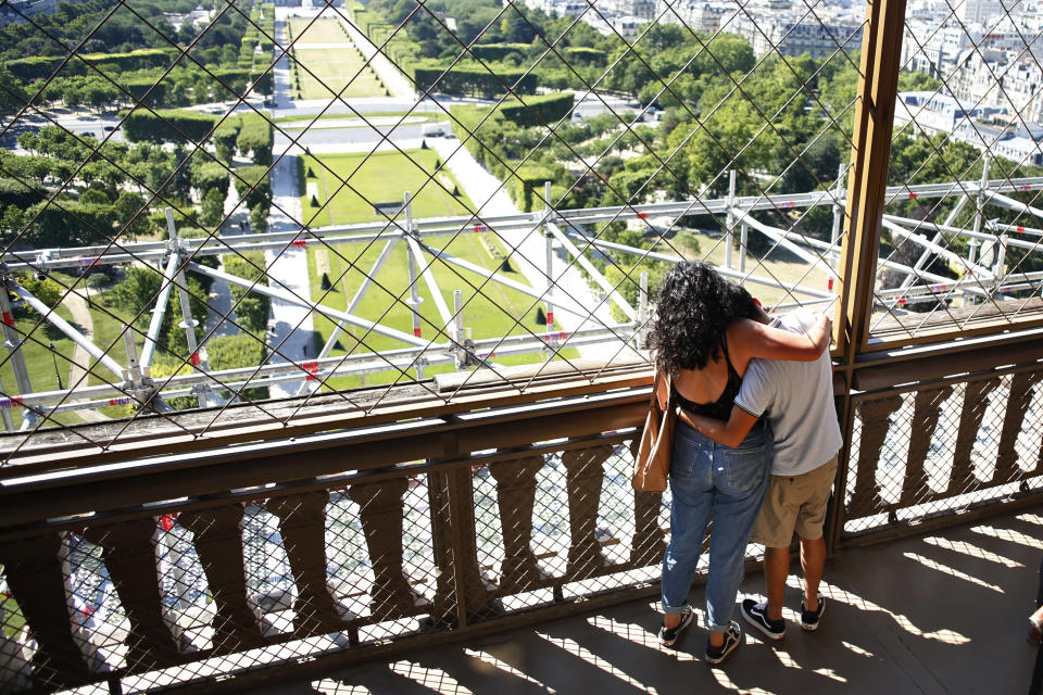 A couple hugs each other as they visit the Eiffel Tower, in Paris, Thursday, June 25, 2020. The Eiffel Tower reopens after the coronavirus pandemic led to the iconic Paris landmark's longest closure since World War II. (AP Photo/Thibault Camus)