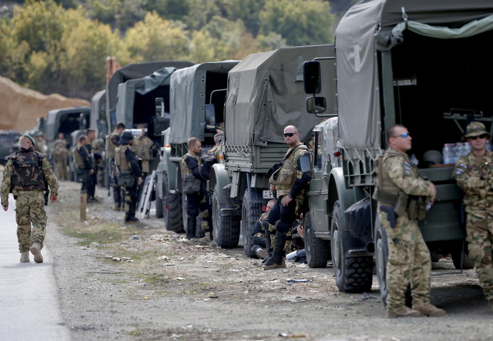 KFOR troops in riot gear stand by near a roadblock in Vojtesh, Kosovo, Sunday, Sept. 9, 2018. Kosovo Albanians burned tires and blocked roads with wooden logs, trucks and heavy machinery on a planned route by Serbia's President Aleksandar Vucic who was trying to reach the village of Banje while visiting Serbs in the former Serbian province. (AP Photo/Visar Kryeziu)