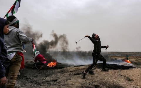 A Palestinian protester uses a slingshot to hurl a rock towards Israeli forces - Credit: MAHMUD HAMS/AFP