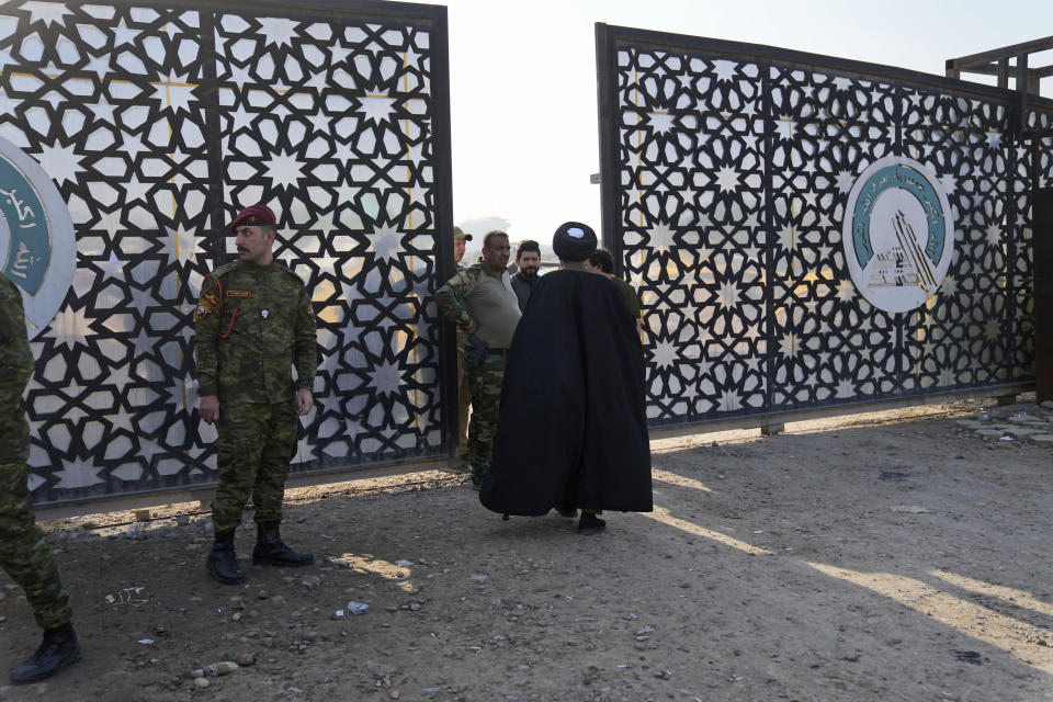 Members of an Iraqi Shiite militant group stand outside the headquarters of the Popular Mobilization Force after it was hit by an airstrike in Baghdad, Iraq, Thursday, Jan. 4, 2024. The Popular Mobilization Force - a coalition of militias that is nominally under the control of the Iraqi military - announced in a statement that its deputy head of operations in Baghdad, Mushtaq Taleb al-Saidi, or "Abu Taqwa," had been killed in the strike. (AP Photo/Hadi Mizban)