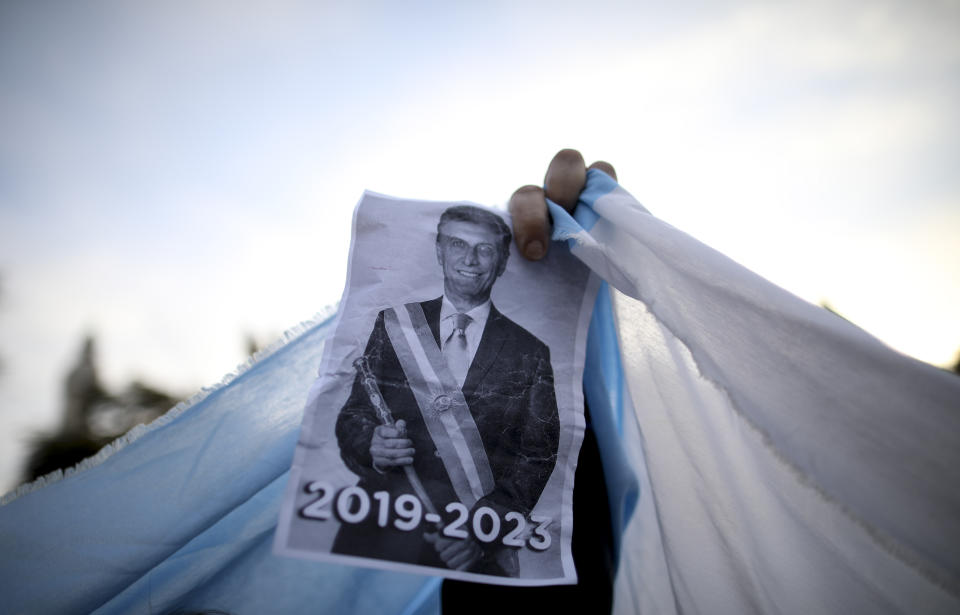 FILE - In this Aug. 24, 2019 file photo, a sopporter holds up an image of President Mauricio Macri during a march in Buenos Aires, Argentina. Many farmers and ranchers expected Macri to be re-elected president of Argentina. Now, farmers are bracing for a return of interventionist policies if a populist ticket returns to power in the Oct. 27 presidential election. (AP Photo/Natacha Pisarenko, File)