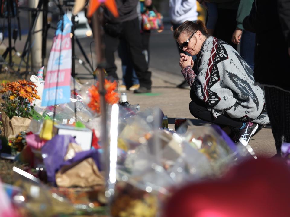 People visit a makeshift memorial near the Club Q nightclub on November 21, 2022 in Colorado Springs, Colorado. On Saturday evening, a 22-year-old gunman entered the LGBTQ nightclub opened fire, killing at least five people and injuring 25 others before being stopped by club patrons.