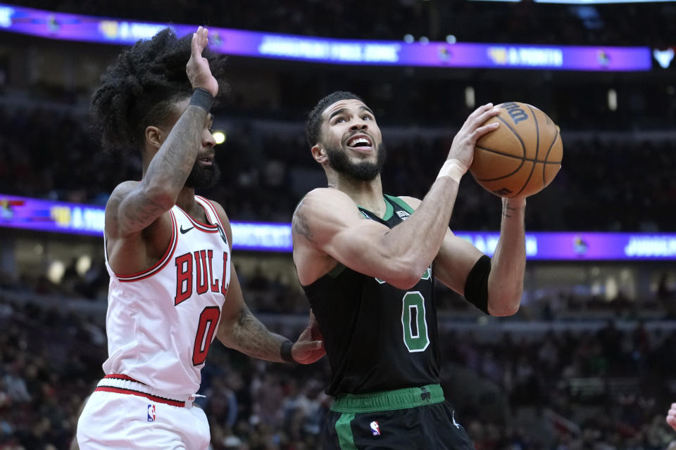 Boston Celtics' Jayson Tatum, right, drives to the basket as Chicago Bulls' Coby White, left, defends during the first half of an NBA basketball game Thursday, Feb. 22, 2024, in Chicago. (AP Photo/Charles Rex Arbogast)