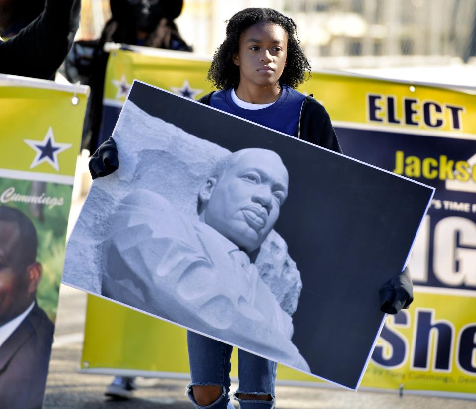 At Jacksonville's 2022 Martin Luther King Jr. parade, Amaya Morgan carries a sign with an image of the statue of the slain civil rights leader in Washington, D.C.