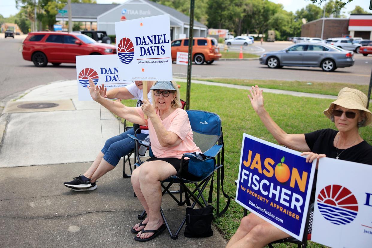 Volunteers, from left, Marcia Morris, Sherry Cook, and Diana Peterson show their support for Republican candidate Daniel Davis by waving at cars passing by Tuesday near Oceanway Community Center in Jacksonville.