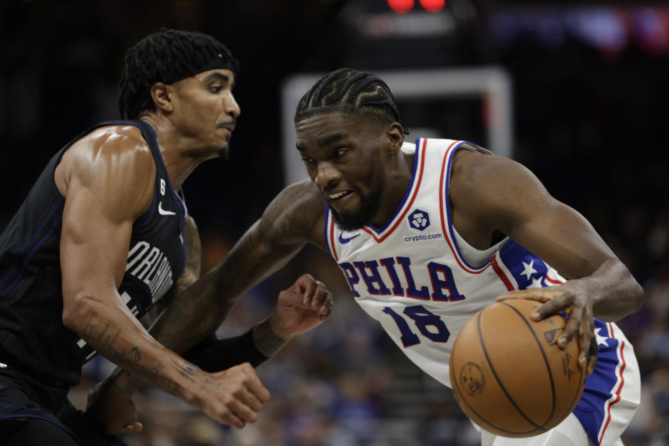 Philadelphia 76ers guard Shake Milton (18) is defended by Orlando Magic guard Gary Harris (14) during the first half of an NBA basketball game, Friday, Nov. 25, 2022, in Orlando, Fla. (AP Photo/Kevin Kolczynski)